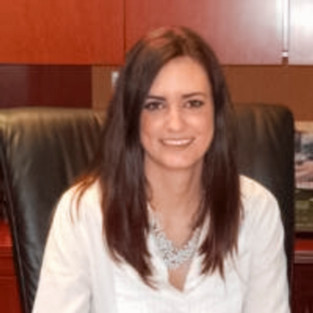 Woman in white button down sitting at office desk. 
