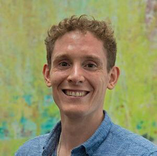 headshot of man wearing blue button down.