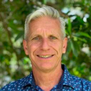 Headshot of man with gray hair wearing blue button down.