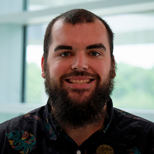 Headshot of a man with beard smiling. 