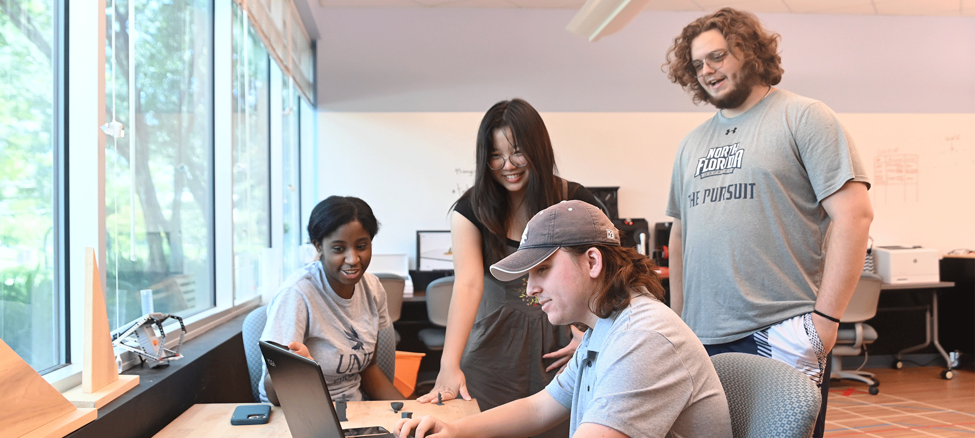 four students around a laptop