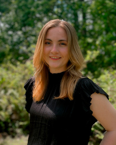 Girl in black shirt in front of blurred green background.
