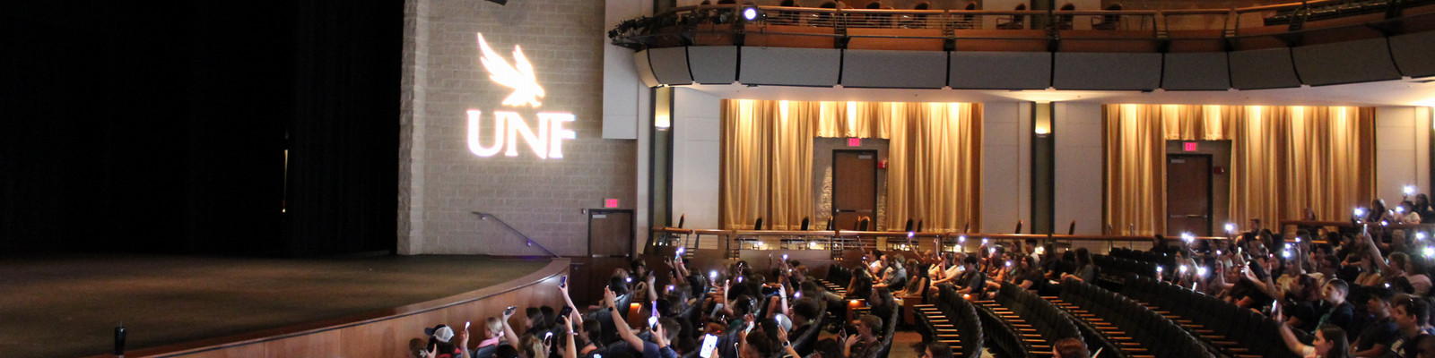 Students shining phone flashlights in a theater