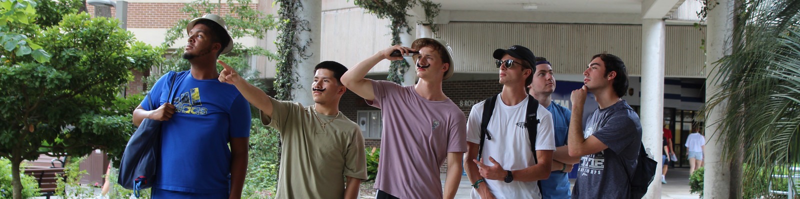 Honors students wearing mustaches and hats while posing. 