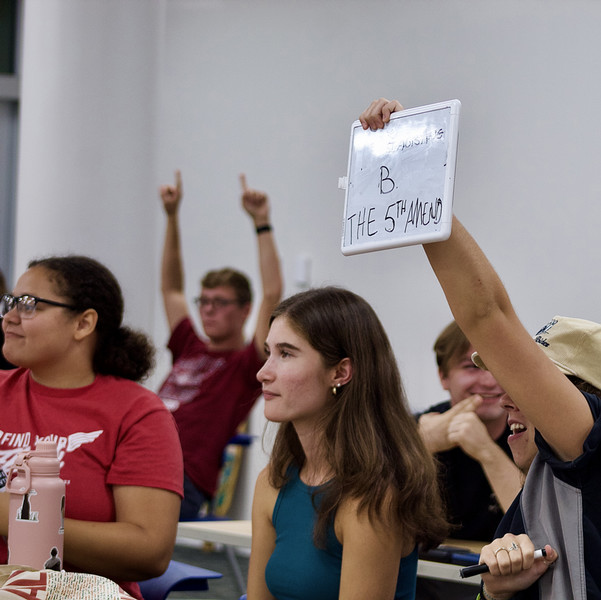 Students holding up small whiteboards while playing trivia.