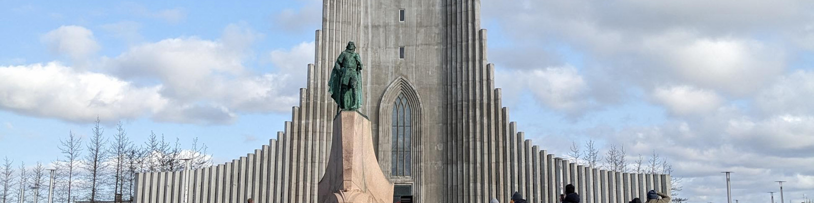 Statue of a man in front of a large, modern styled building.