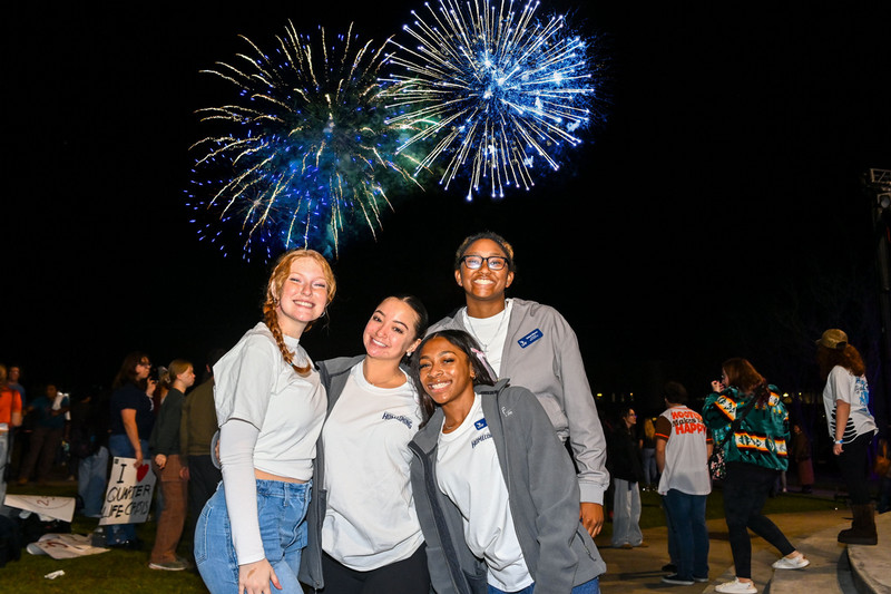  UNF students smiling with fireworks in the background