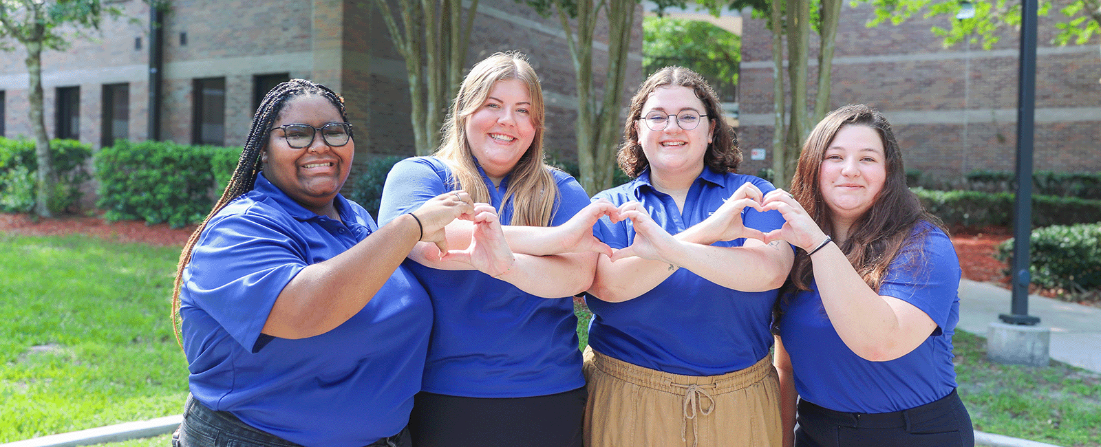 Assistant Residence Life Coordinators smiling and making hearts with their hands