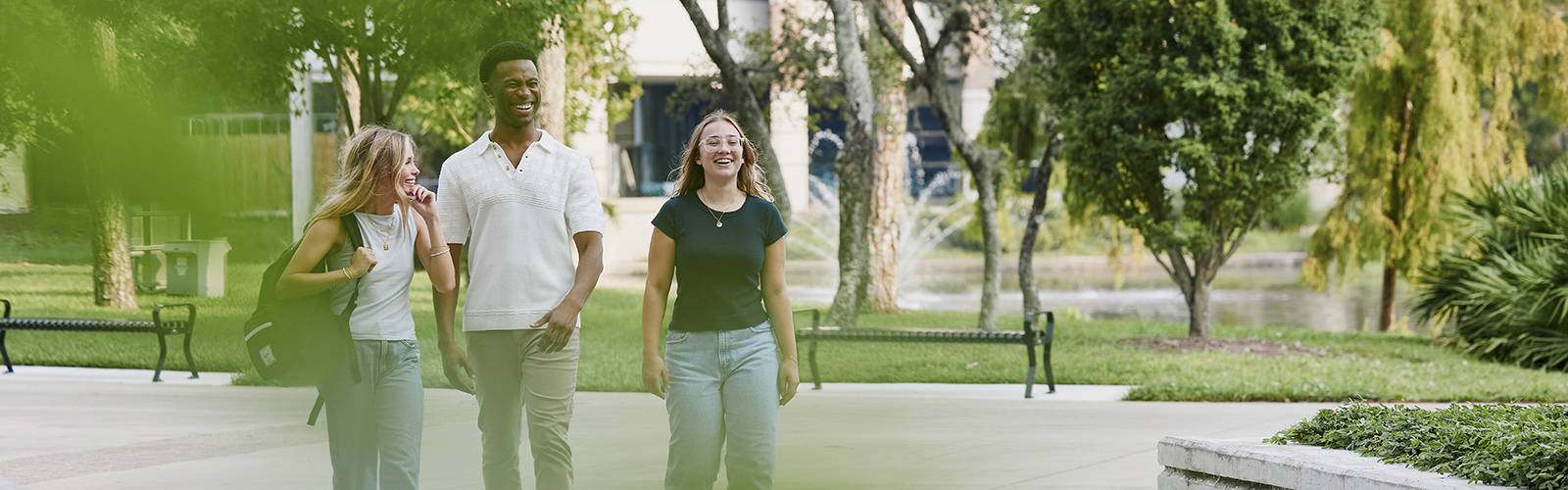three students smiling and laughing on a beautiful day on UNF campus