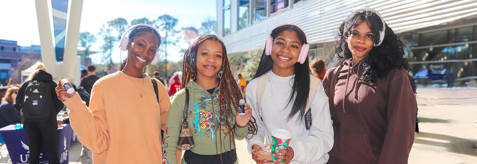 Four friends at UNF market days smiling at the Housing table