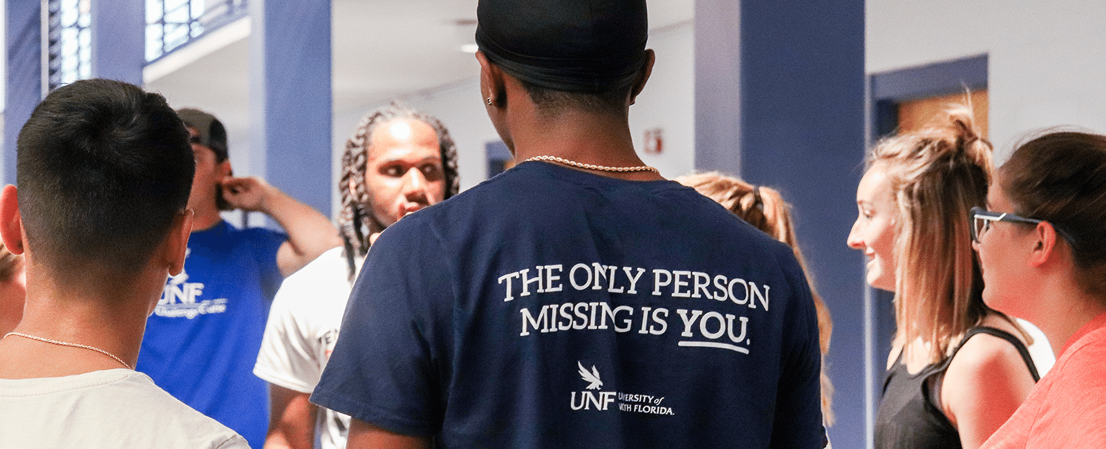 student with a t-shirt saying the only person missing is you with the unf logo
