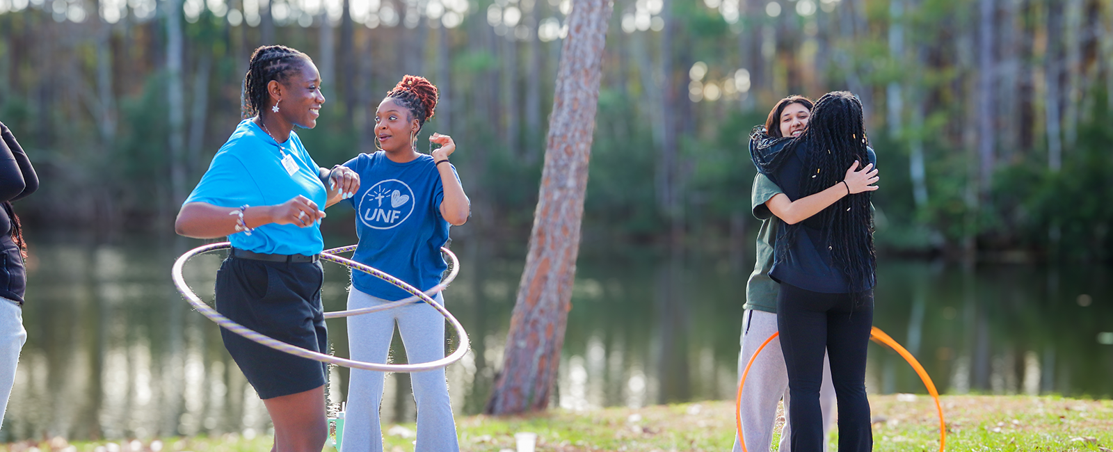 UNF residents during de-stress fest outside of the residence halls. Two students smiling and laughing and another two hugging. 
