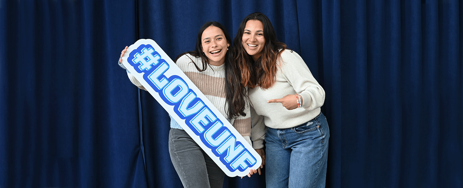 students smiling holding a #LOVEUNF sign