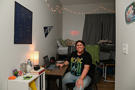 UNF resident sitting at the desk in their handsomely decorated room smiling