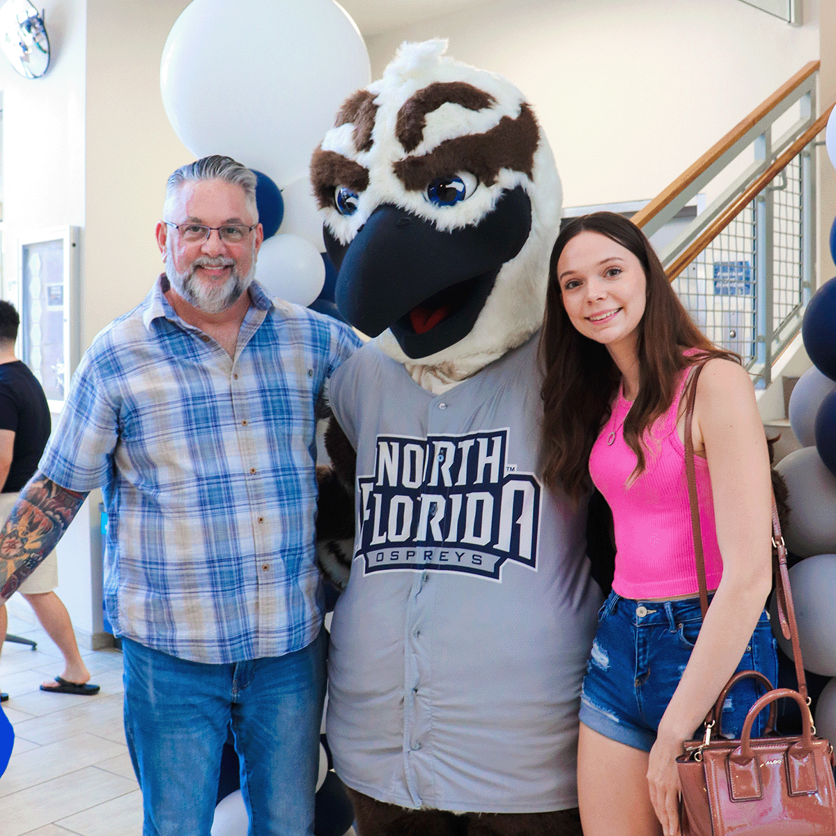Resident and parent smiling with Ozzie on move-in day