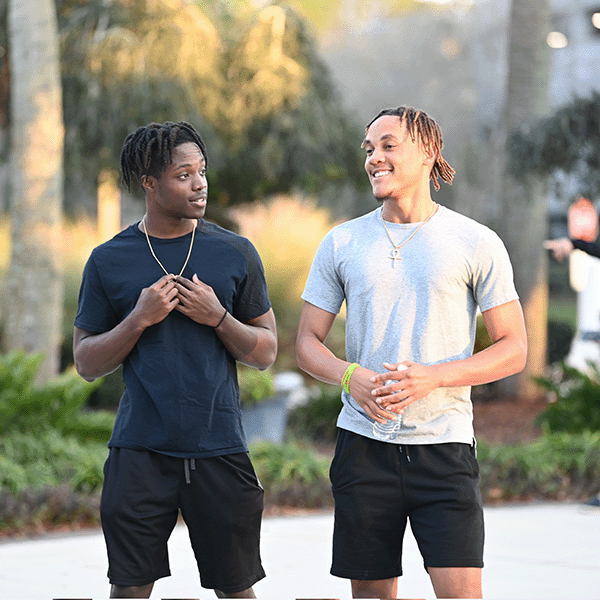 two UNF students walking and talking together on a beautiful day