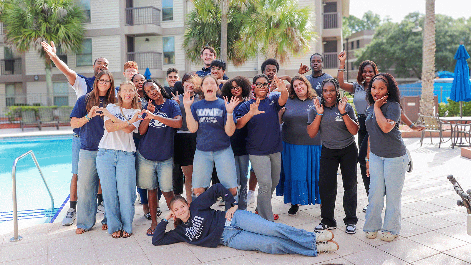 Osprey Landing Student Staff taking a fun photo in front of Osprey Clubhouse wearing UNF apparel