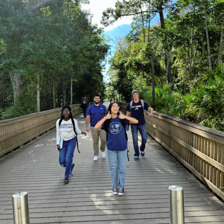 four students walking on the boardwalk smiling