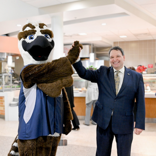President Limayem and mascot Ozzie high five in dining hall.