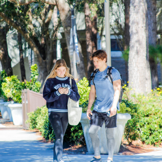 Two students look down and walk on campus