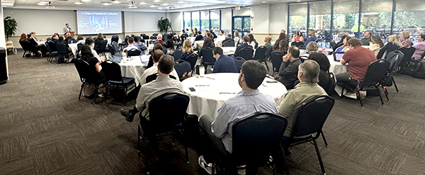 man presenting at UNF AI Symposium to a crowd of people