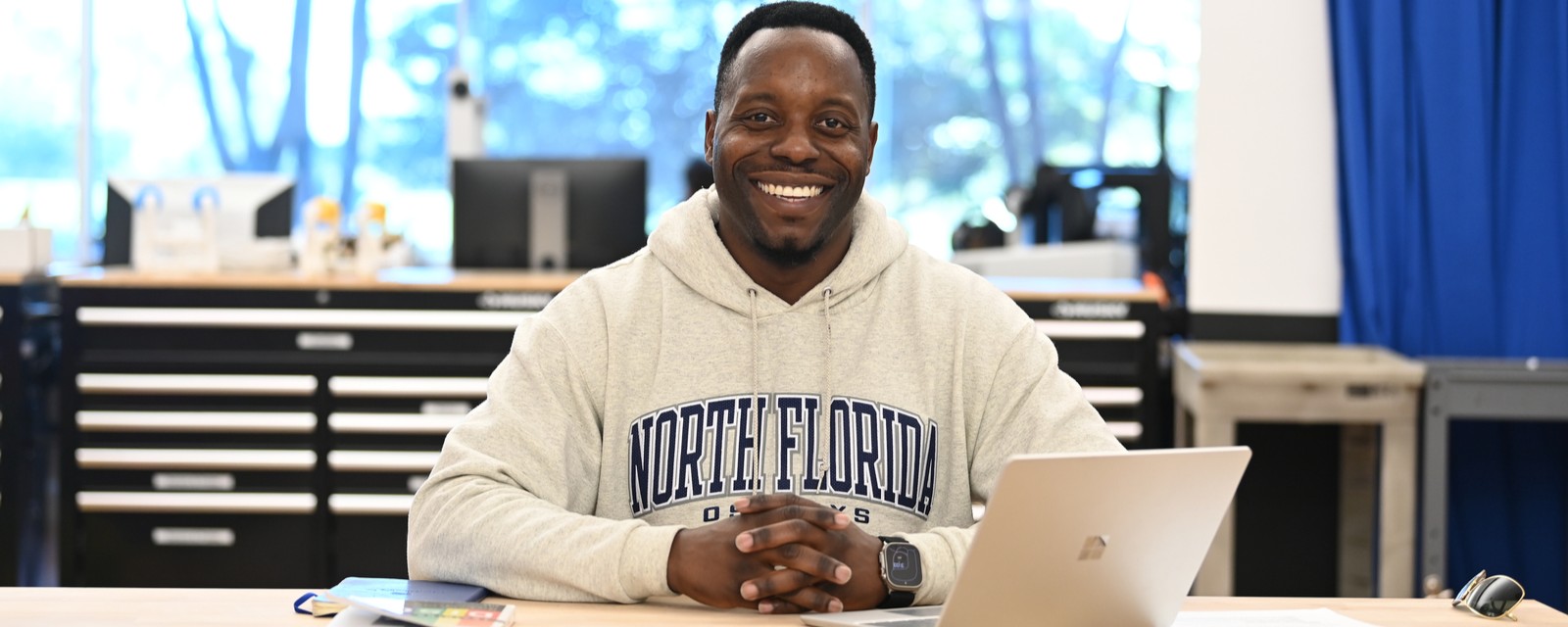 Student smiling holding a laptop