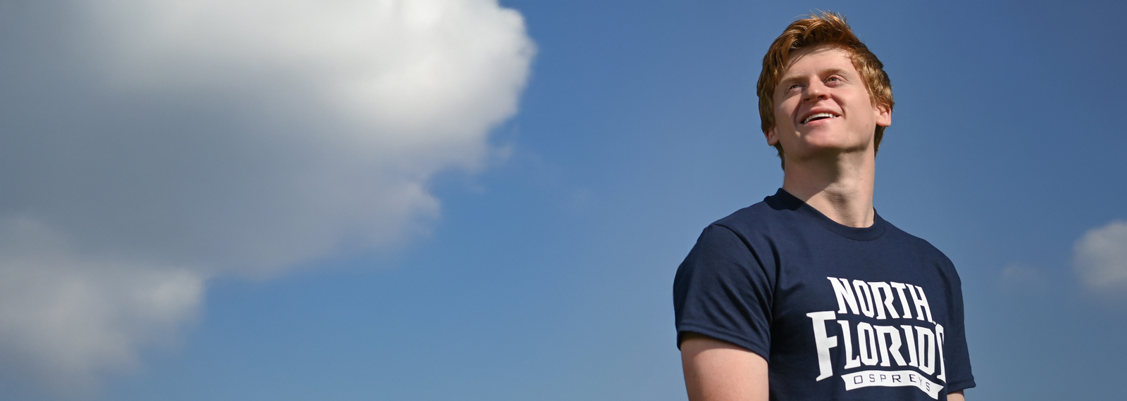 student gazing northward against a cloudy blue sky