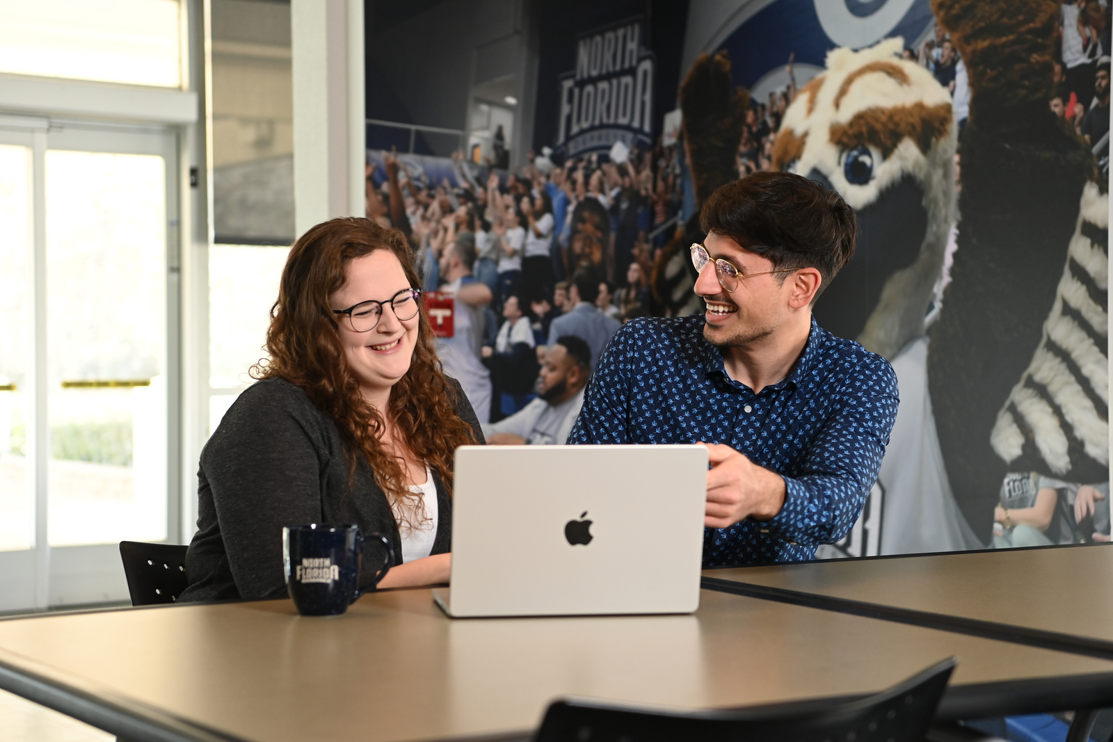 Two employee smiling at a laptop