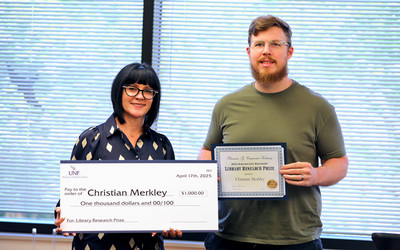 Woman presenting giant check prize to student