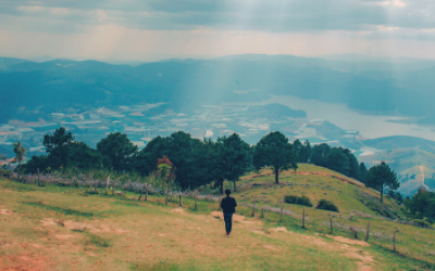 A person stands on a hill overlooking a mountain vista.