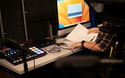 Picture of the desk in the UNF recording studio with various sound equipment and someone holding a stack of papers