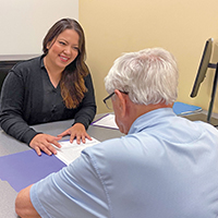 An older man talking with a woman at a desk