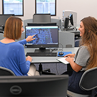 Dr. Amber Barnes and Kelly Rhoden looking at map data on a computer