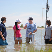 Retired faculty member Dr. Don Resio and students standing in the water