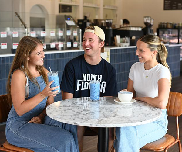 three students talking in a coffee shop