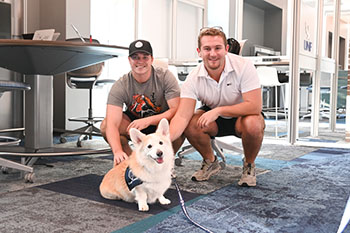 Campus Canine dog and two male students in UNF library