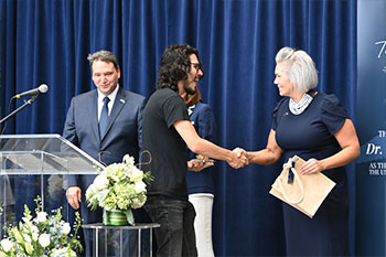 Student shaking hands after receiving scholarship at campus celebration after Inauguration