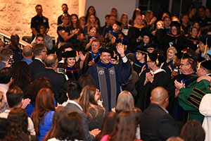 President Limayem enters the Lazzara Theatre during Inauguration waving at the standing audience
