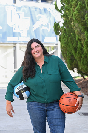 Nikki Mejido standing with a volleyball under one arm and a basketball in the other hand