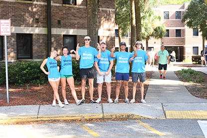 Group of UNF students posing for a photo in front of the dorms