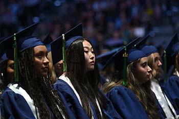 Female UNF graduates sitting at 2023 commencement ceremony