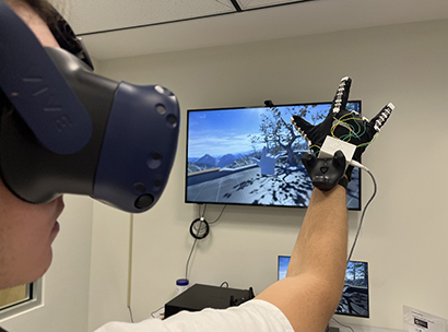 Man wearing a virtual reality headset  holding his hand in a glove against a screen