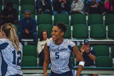 UNF volleyball player Mahalia sharing a laugh on the court with teammates