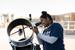 Female UNF student looking through a telescope