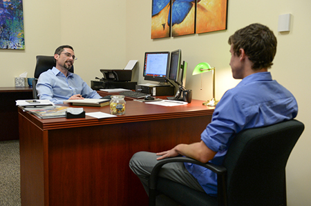 Professor sitting in his office speaking with a student