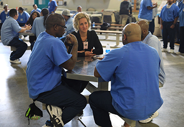 UNF professor sitting at a table speaking with prison inmates