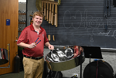 Shaun Bennett standing next to a steelpan