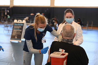 Nurses administering a COVID shot to a gentleman