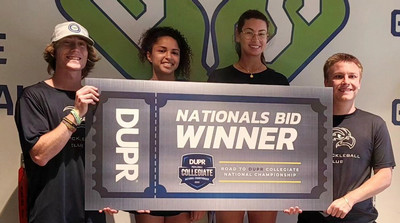 Members of the UNF Pickleball Club holding a National Bid Winner banner