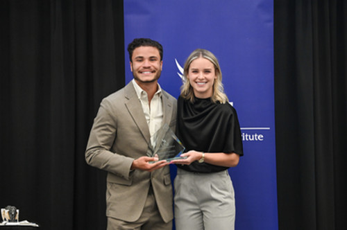 Man and woman holding an award at an award ceremony